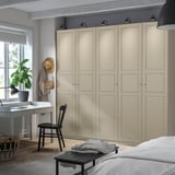 Cozy room with large light beige PAX wardrobe, dark wood desk, chair, and basket.