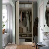 Closed wardrobe with organized clothes, storage baskets, and boots. Light-colored doors and walls.