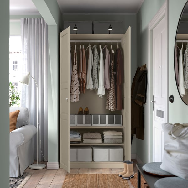Open wardrobe with hangers, folded clothes, boxes, and lighting.