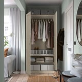 Open wardrobe with hangers, folded clothes, boxes, and lighting.