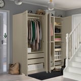 An open wardrobe unit displays clothes, accessories, and storage solutions in an organized entryway.
