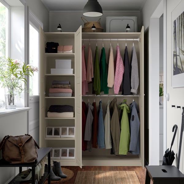 Open wardrobe with clothes hangers, folded sweaters, bags, and boxes. Shelves with adjustable hangers, lit top section.