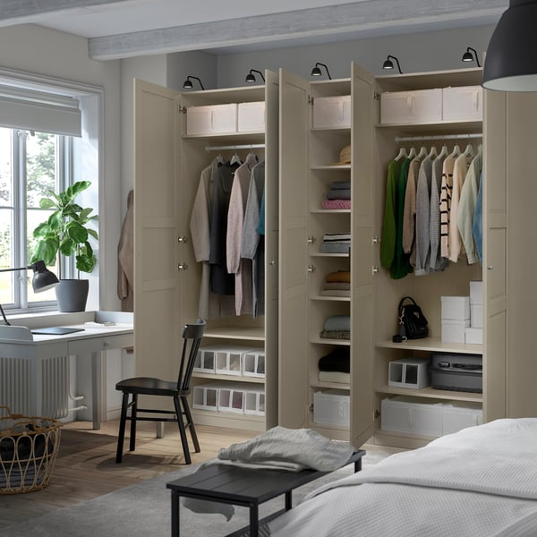 Bedroom with an open beige PAX wardrobe showing clothes, shelves, and organized storage.