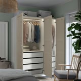 Modern bedroom with beige PAX wardrobe, clothes, drawers, and lighting.