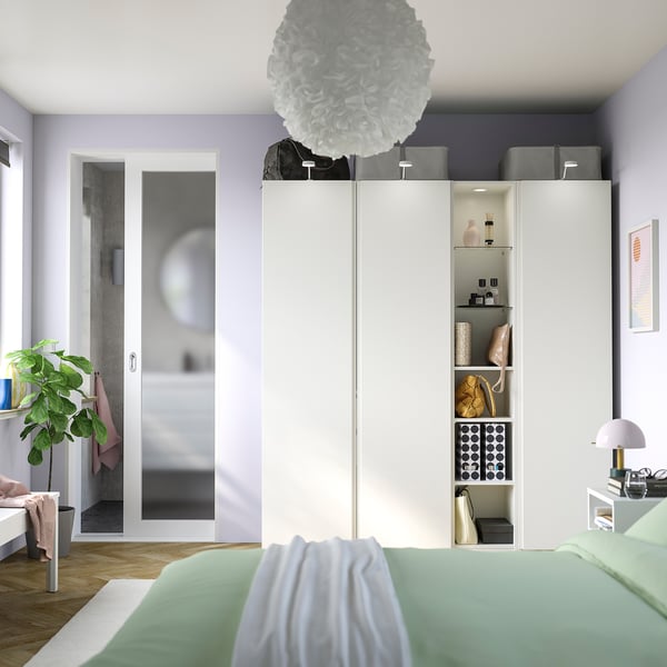 Modern bedroom with PAX wardrobe, spherical light, green bed linens, glass door, plant.