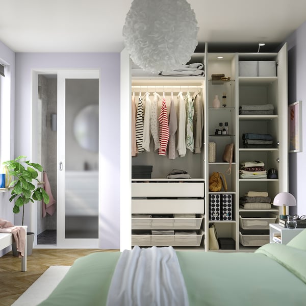 A modern bedroom featuring a PAX wardrobe with drawers, shelves, and hanging space for organized storage.