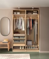 Organized PAX wardrobe in light wood; hangers, shelves, glass drawers.