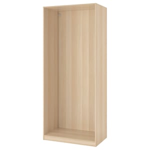 An ikea PAX wardrobe frame in white/bleached wood. Its rectangular, tall, and open-fronted with adjustable feet.