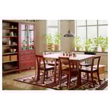 Bright dining scene with PINNTORP red wood table and chairs, patterned rug, plants, and red cabinet.
