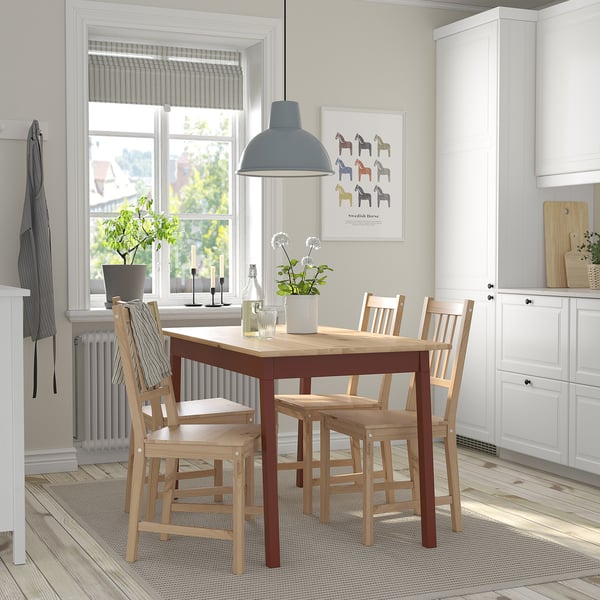 Cosy dining nook with 4-seat table near window, set with decor. Wooden chairs, lamp, and poster. Compact.