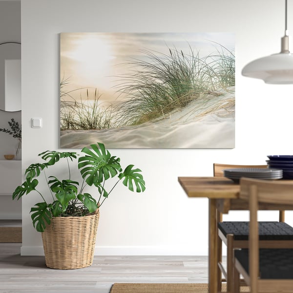 Large wall art on white wall, massive green plant in wicker basket beside wooden dining table with black chairs.