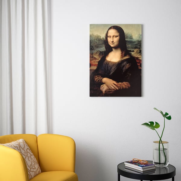 Minimalist room with yellow PJÄTTERYD chair, leonardo da vinci portrait, and small table with books and plant.
