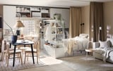 Modern studio apartment featuring PLATSA bed in white, combining sleep and storage, with beige curtains, wooden dining set, and tasteful decor.
