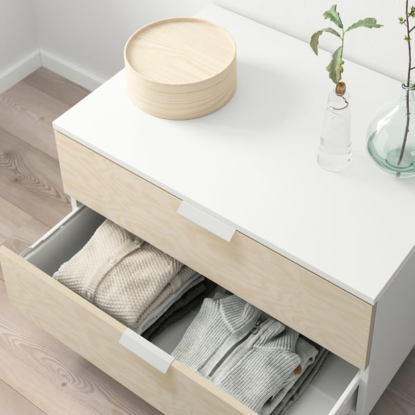 White PLATSA dresser shows open drawer filled with folded clothes, stacked wooden discs atop.