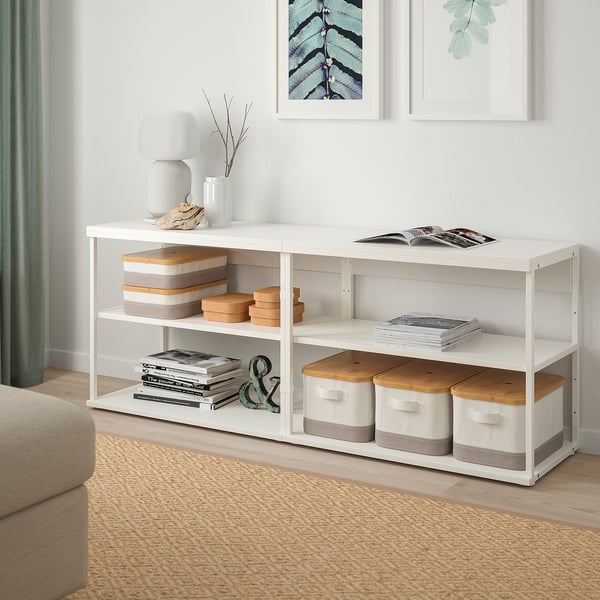 PLATSA white storage unit, slim yet tall, fits neatly next to a beige sofa. Stores books, decor, and has open sections.