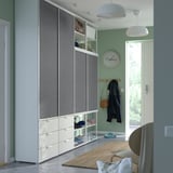 Modern entryway with tall gray PLATSA wardrobe, shelves, and hanging items. Sliding doors and a clothes rail.