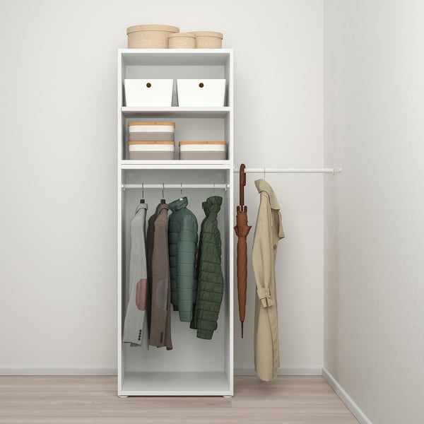A tall, narrow white storage unit with shelves holding baskets and boxes, and a clothes rail below holding jackets and an umbrella.