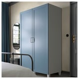 Blue PLATSA wardrobe, modern design, next to bed, light grey walls, gold door handles, mirror and window.