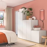 Cozy bedroom with pink walls, white PLATSA storage units, orange bedding, and wooden decor.