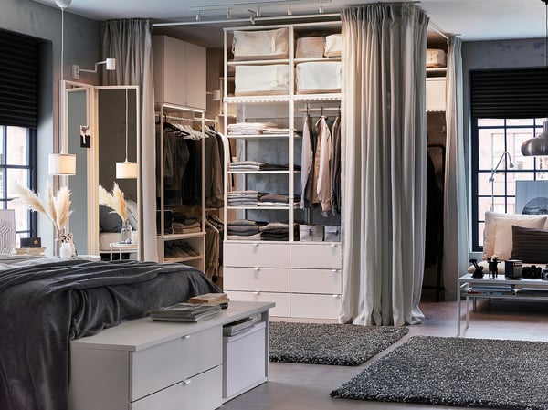 Modern bedroom with white PLATSA storage, mirror, and gray curtain.