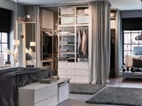 Modern bedroom with white PLATSA storage, mirror, and gray curtain.