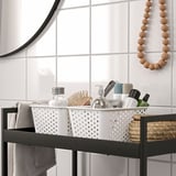 Bathroom storage basket organizes toiletries and beauty products on shelves.