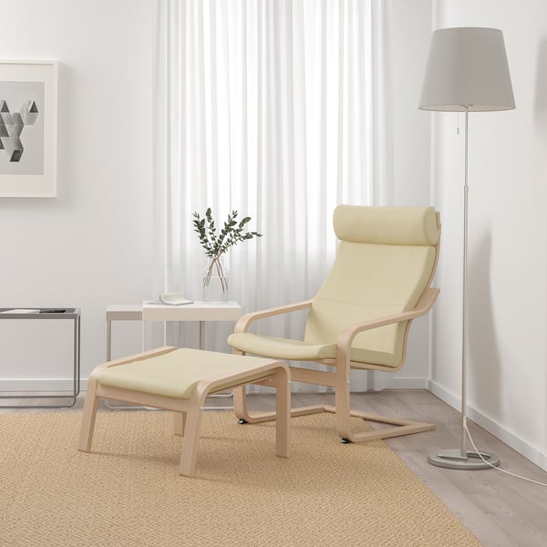 Modern living room with beige POÄNG armchair & ottoman. Soft leather, curved wood frame. Floor lamp & side table. Neutral decor.