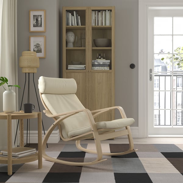 Modern living room with rocking chair, cabinet, rug. Chair has headrest & cushions. Balcony doors & decor visible.