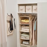 Organized closet with hanging storage compartments for folded clothes and hanging garments, utilizing space efficiently.