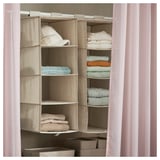 A beige hanging storage unit with multiple compartments, neatly organizing folded clothes.