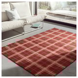 Modern living room with white sofa, red tartan rug, concrete floor, and large window.