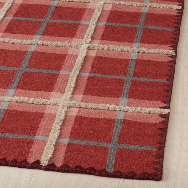 Red plaid rug, hand-woven with quality wool and cotton. Intricate stitching and varied pile heights for a luxurious feel.