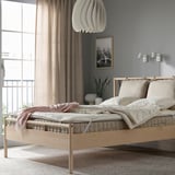 Cozy bedroom with light wooden bed, large windows, minimalist design, neat bedding.