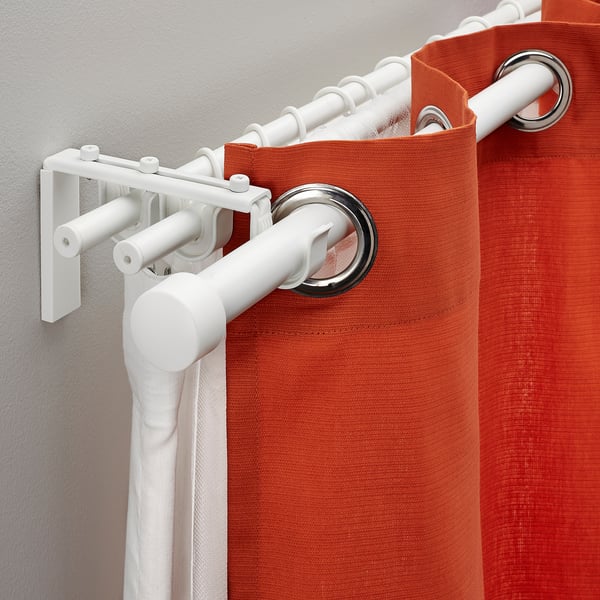 White curtain rod system holding orange curtains, showcasing flexibility with multiple rod holders and adjustable length.