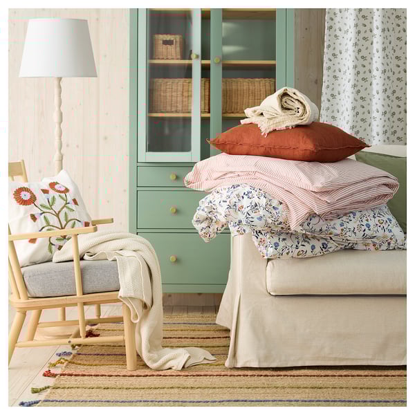 Cozy living room with RAKLEV rug, armchair, green cabinet, and bed.