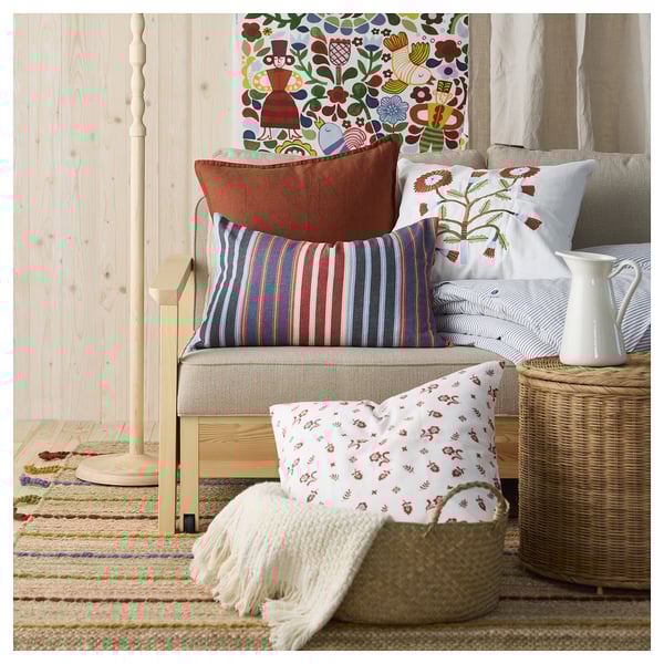 Brightly colored pillows and woven rugs decorate a cozy corner with wooden walls.