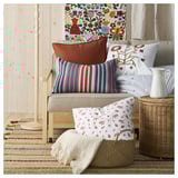 Brightly colored pillows and woven rugs decorate a cozy corner with wooden walls.