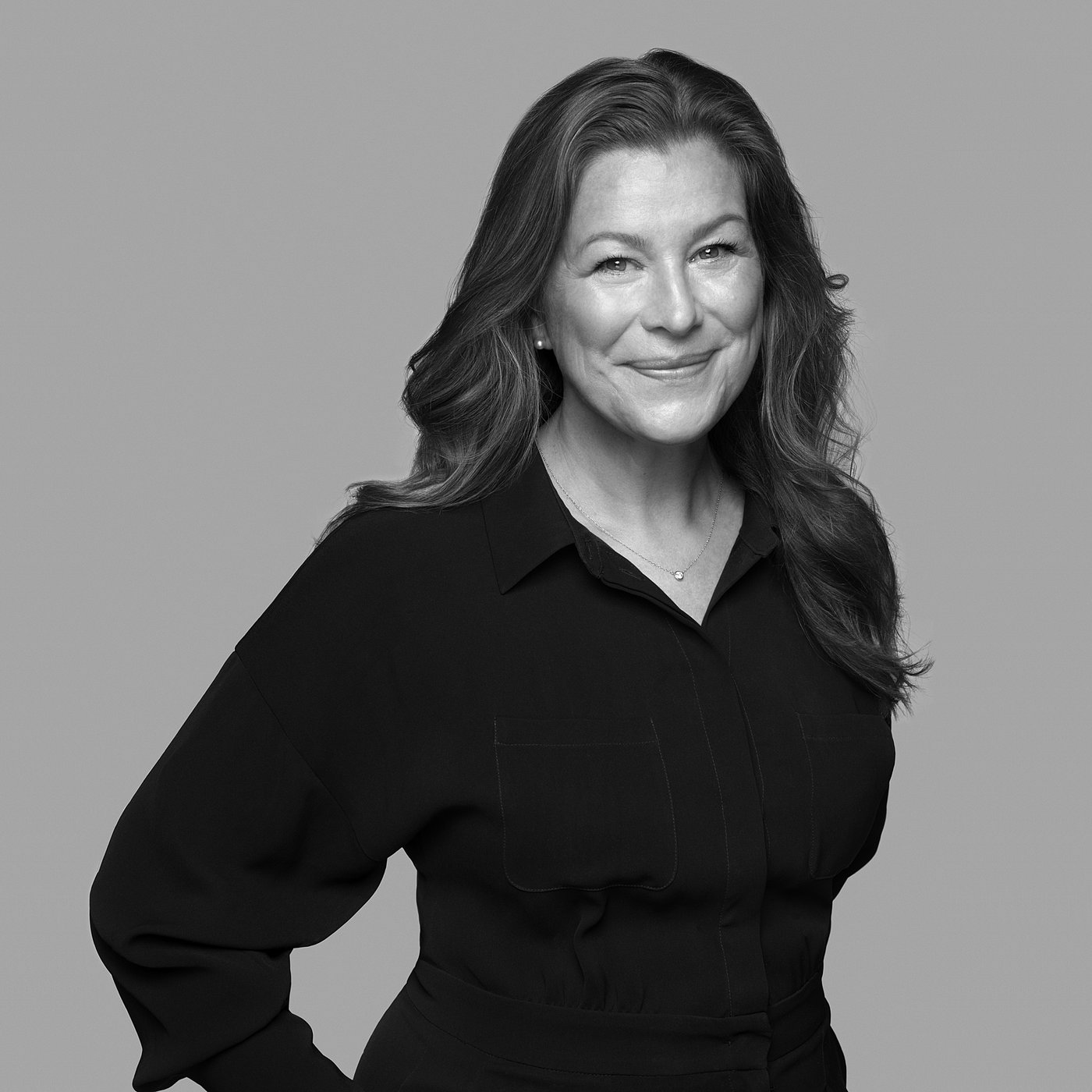 Black and white portrait of Lisa Hilland wearing a black shirt, smiling slightly, with long hair.