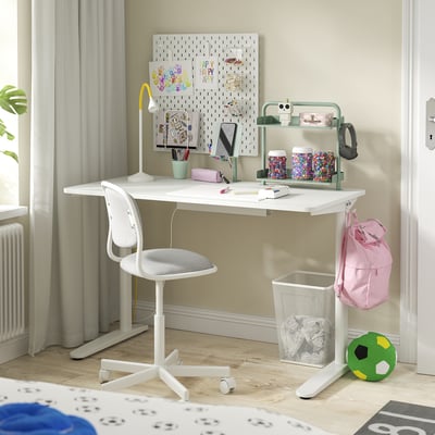 Small kids white desk with storage, phone holder, hooks. Bright, clean, organized space with chair and accessories.