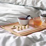 Wooden bed tray with food and drink. Foldable legs, steady for reading or working in bed.