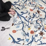Person is crafting with colorful floral pattern fabric, scissors and pins nearby.