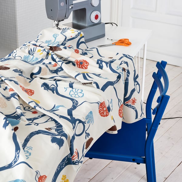 A sewing machine on a table with colorful, patterned fabric draped over it, ready for crafting.