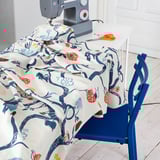 A sewing machine on a table with colorful, patterned fabric draped over it, ready for crafting.