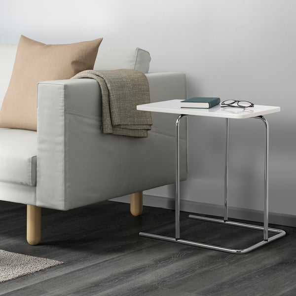 Modern living room showing a gray sofa with a side table next to it. The table has a book and glasses on top.