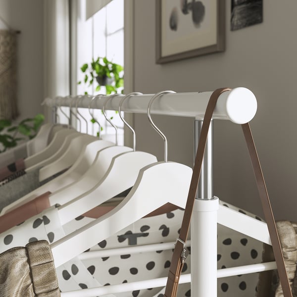 White RIGGA clothes rack with adjustable height, holding several hangers with garments.