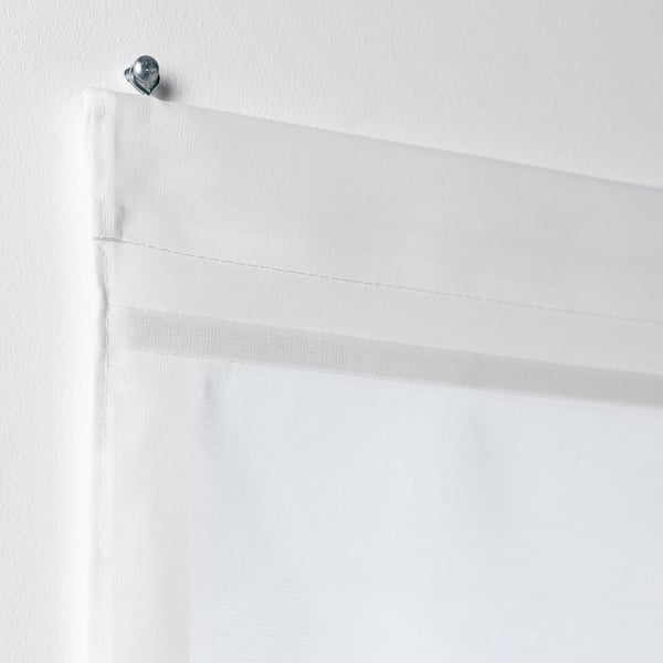 White RINGBLOMMA roman blind, cordless, mounted with metallic ring on wall, raised to show fabric and magnets.