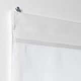 White RINGBLOMMA roman blind, cordless, mounted with metallic ring on wall, raised to show fabric and magnets.