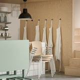 Aprons, chairs, and kitchen items on wooden wall.