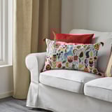 A white sofa with a vibrant, colorful floral pillow featuring tassels and a solid red pillow, emphasizing comfort and decorative appeal.