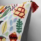 Colorful embroidered pillow with leaf patterns and red tassel, showcasing intricate design and high-quality artisanship.